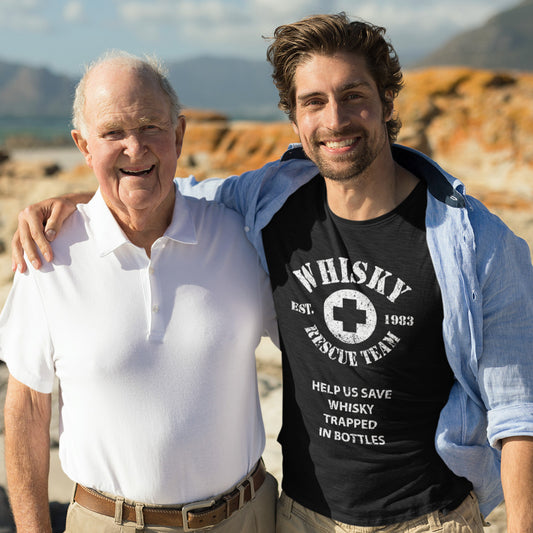 Man at the mountains with his dad wearing a black tshirt that states whisky rescue team help us save whisky trapped in bottles established 1983
