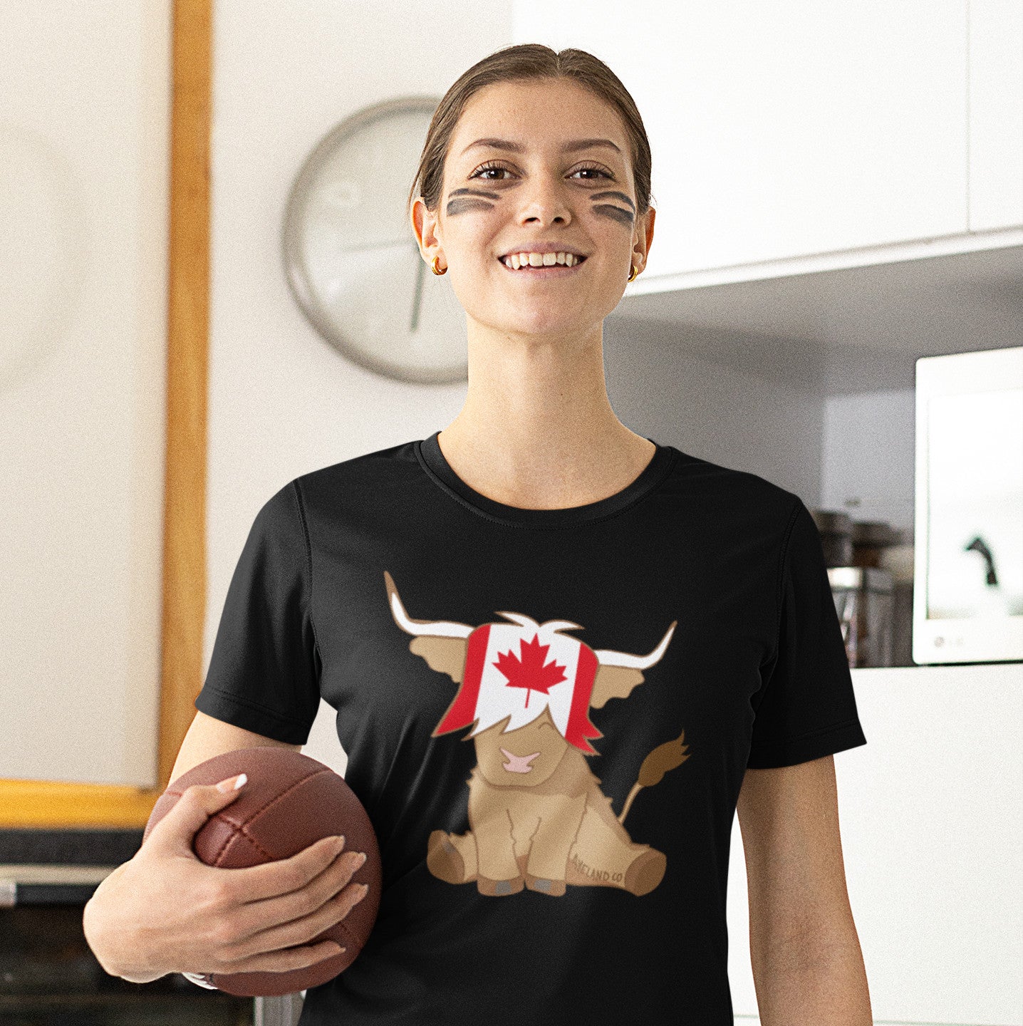 woman wearing a black thsirt with a candian flag highland cow