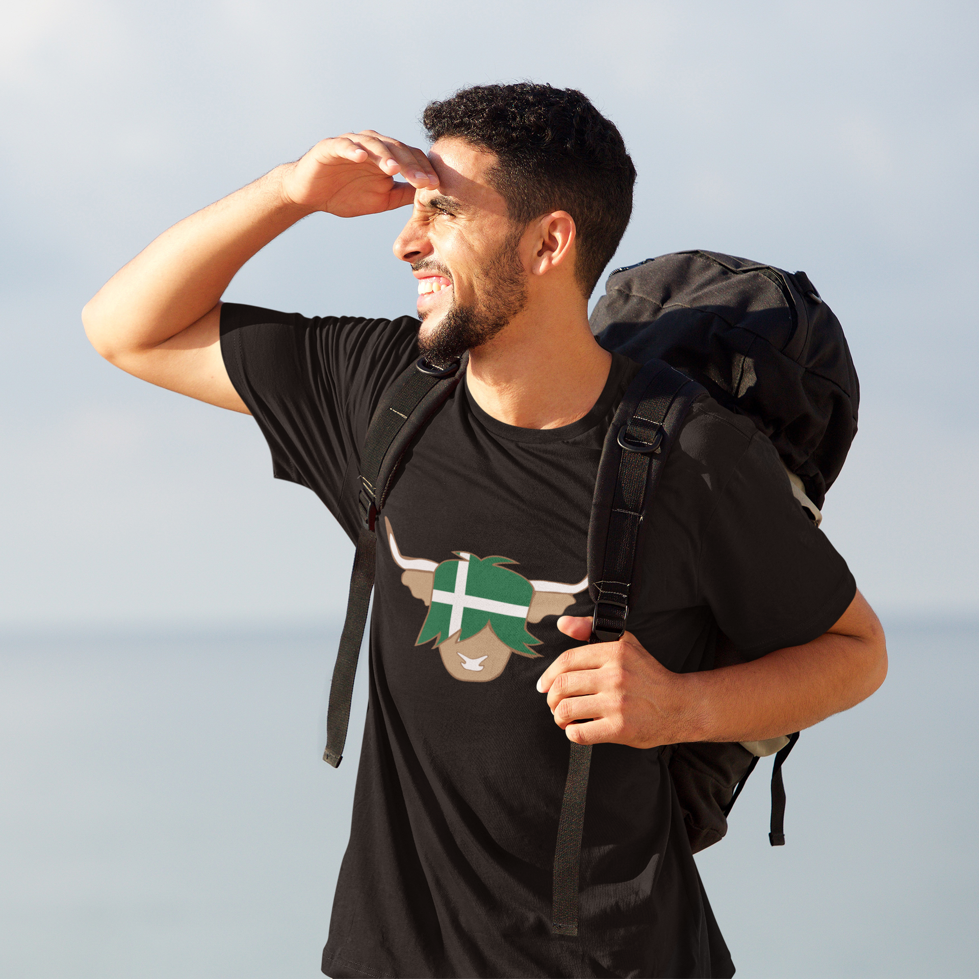 a-man-backpacking-wearing-a-highland-cow-black tshirt-with-barra-island-flag